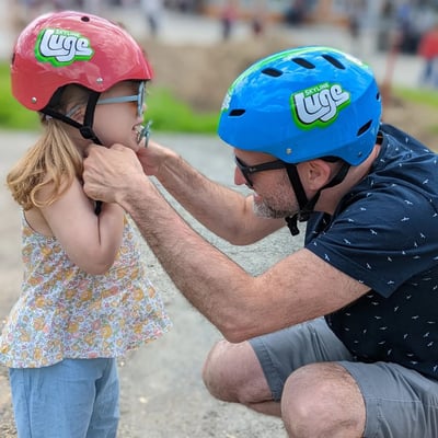 A father makes sure his daughters Luge helmet is tight and secure.