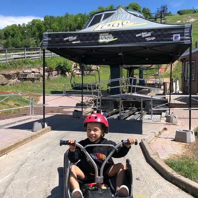 A small kid poses for a photo in his Luge cart at Skyline Luge Mont Tremblant.