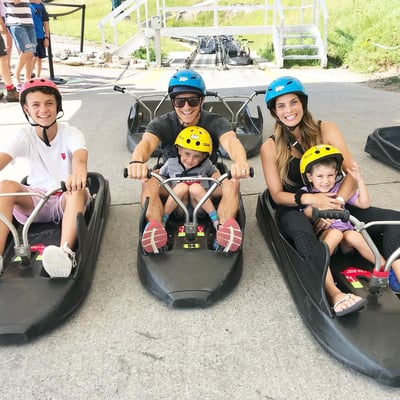 A family poses for a photo in their Luge carts ready to ride the tracks.