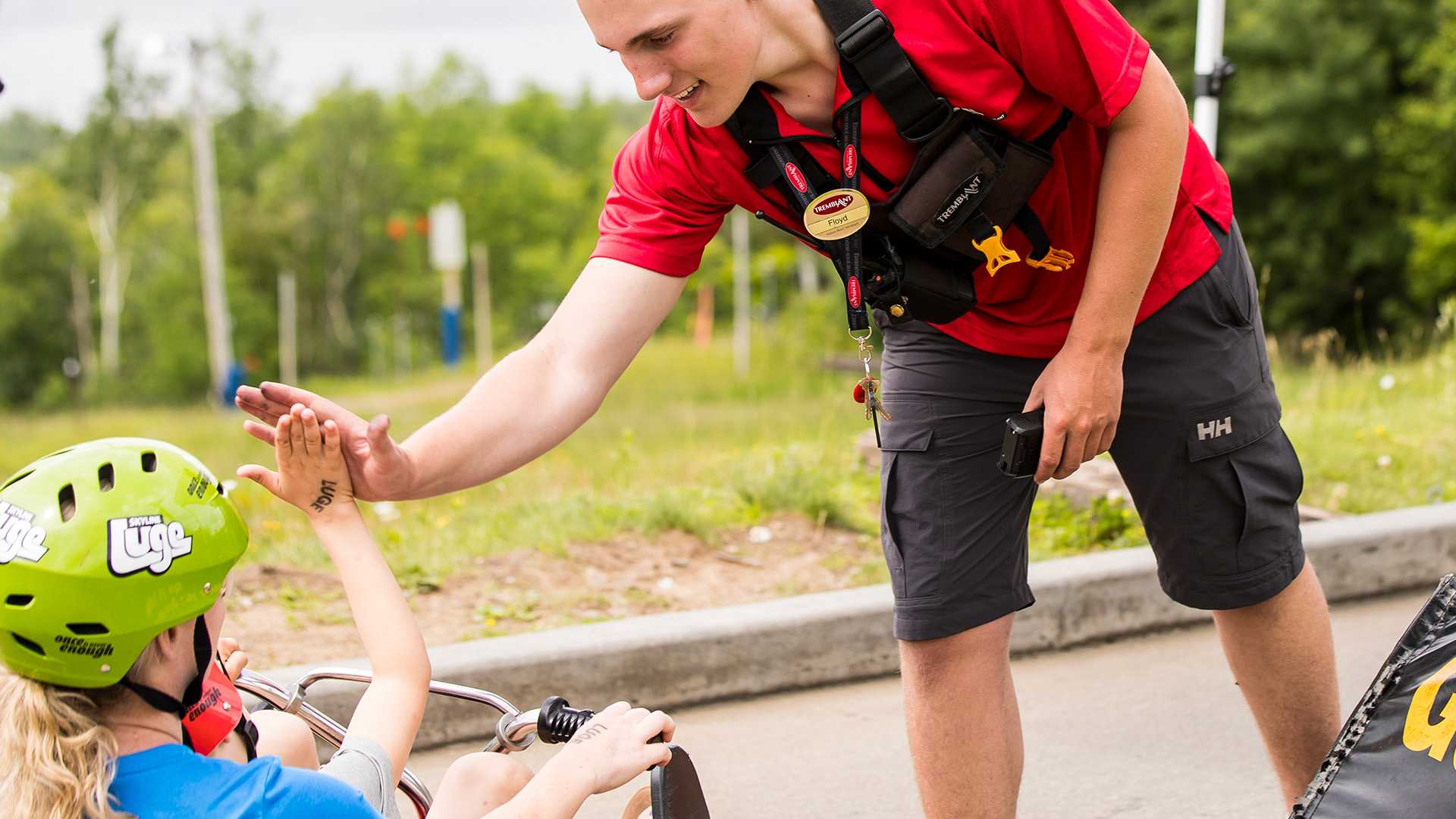 A Skyline Luge Mont Tremblant employee gives a small child a high-five before they head down the tracks.