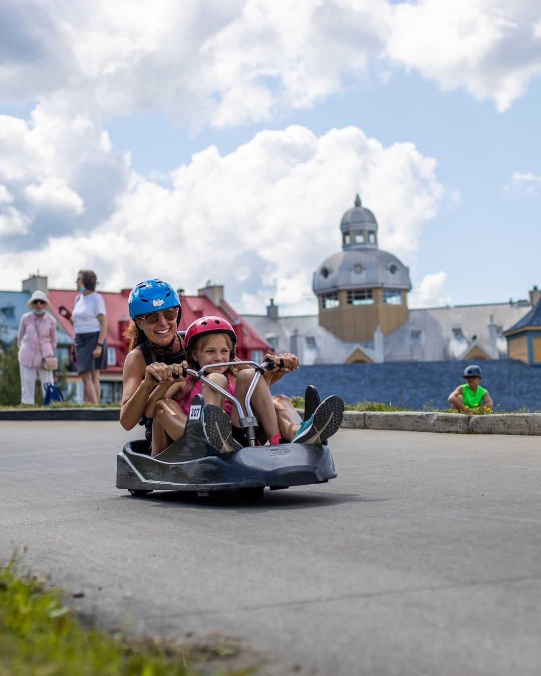 A mother rides down the Luge with her daughter in the same cart.