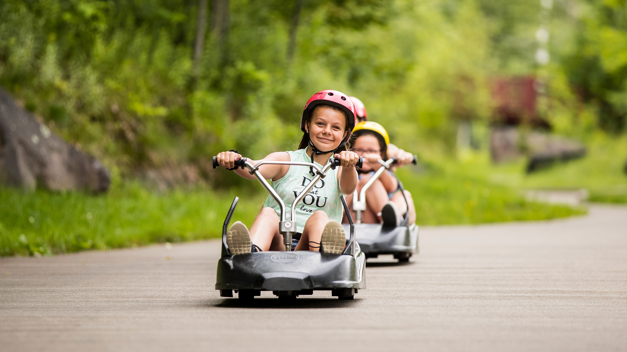 A small girl smiles as she heads down the tracks at Skyline Luge Mont Tremblant.