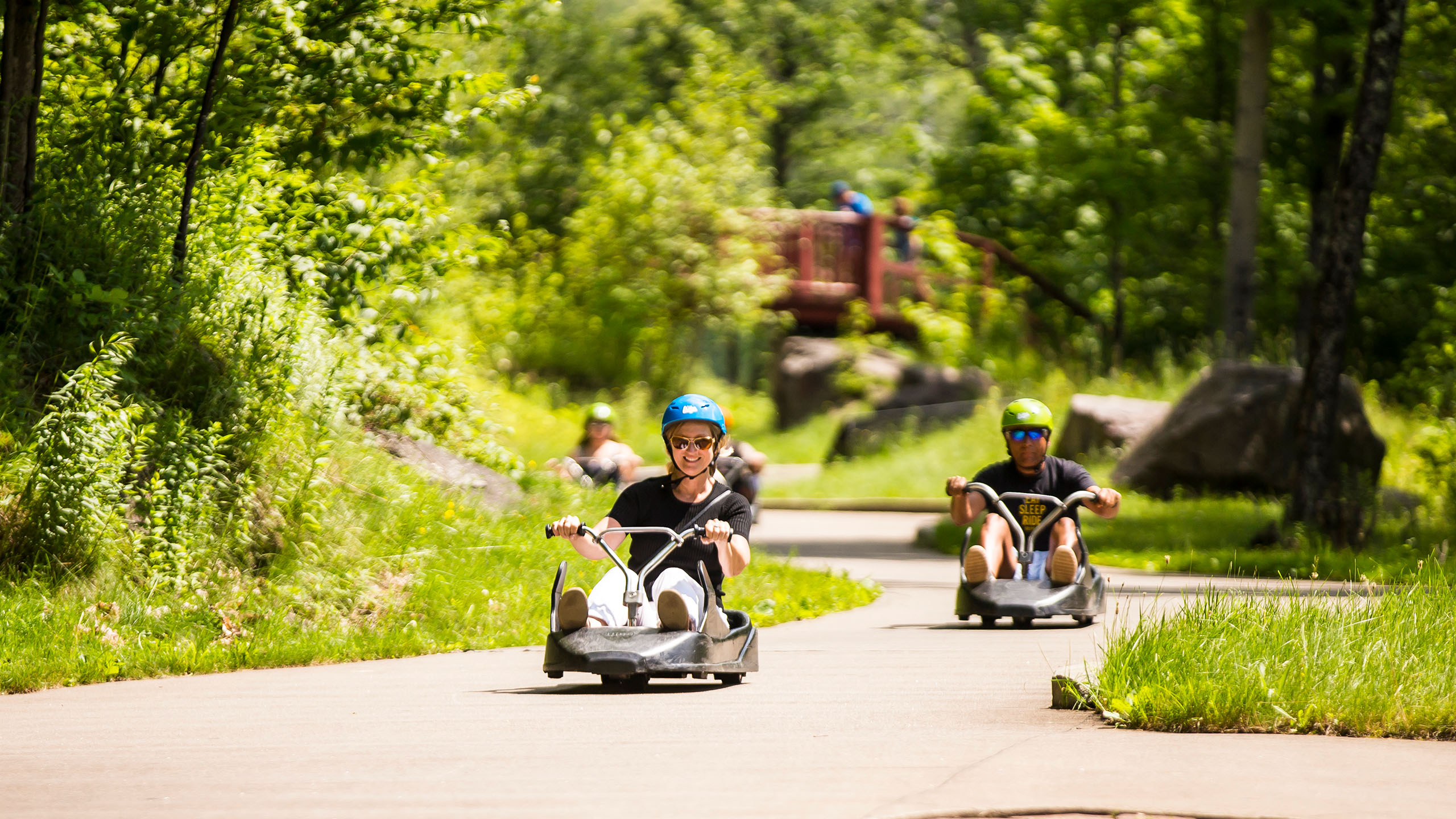 A lady grins as she races down the Skyline Luge Mont Tremblant track.