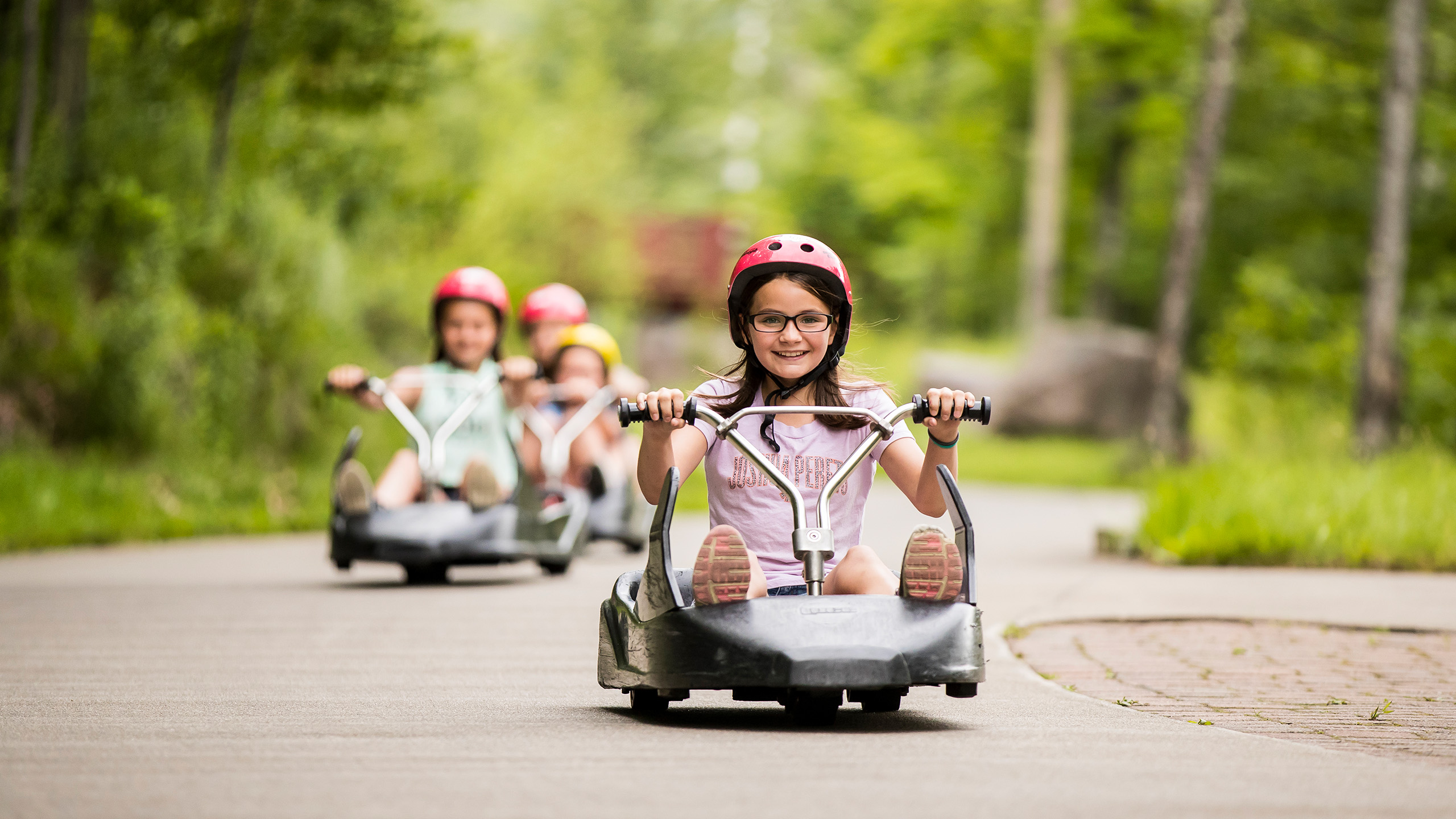 A small girl smiles as she rides down the Skyline Luge Mont Tremblant track.