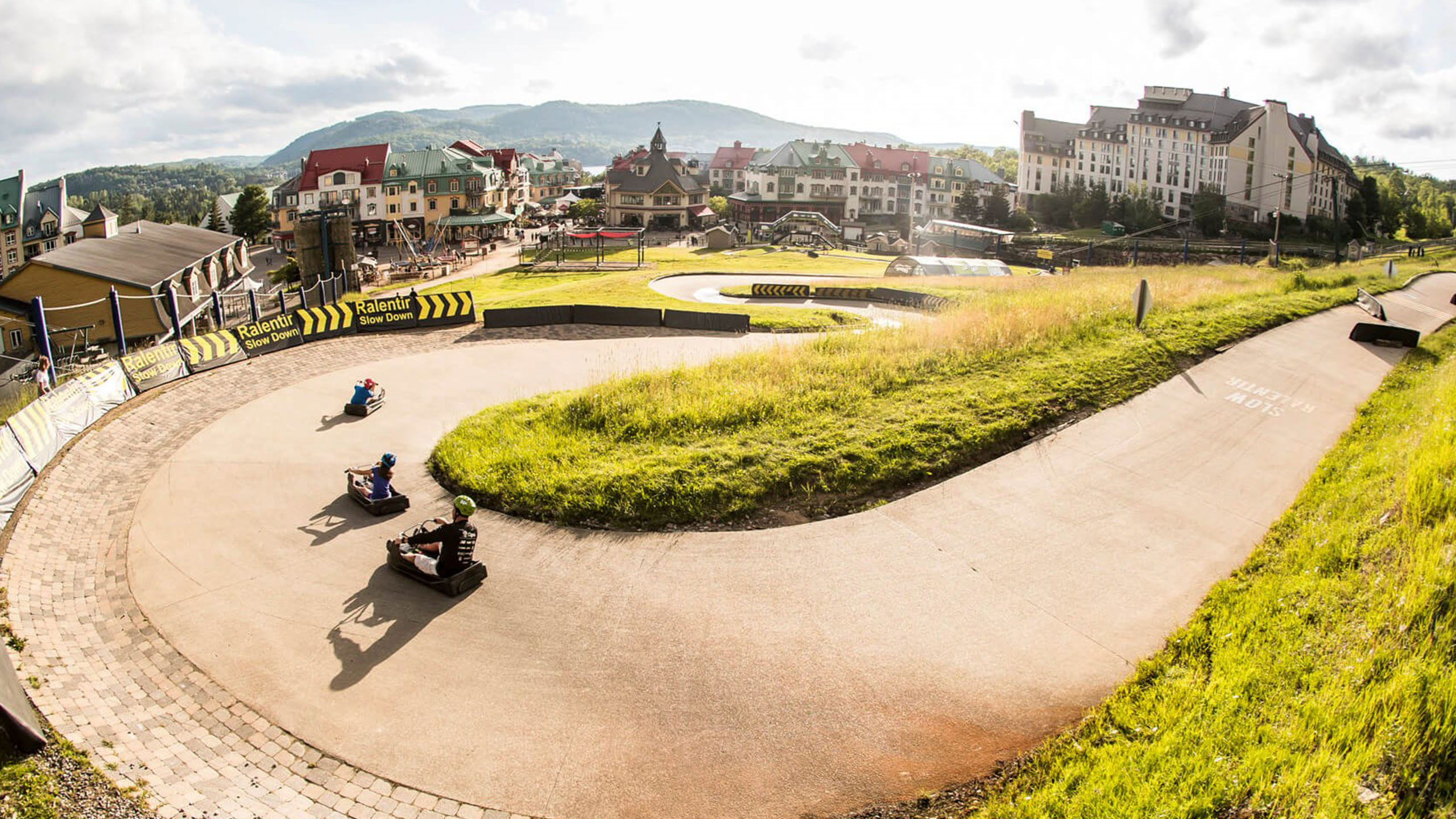 A group of customers ride around a large horseshoe corner at Skyline Luge Mont Tremblant.